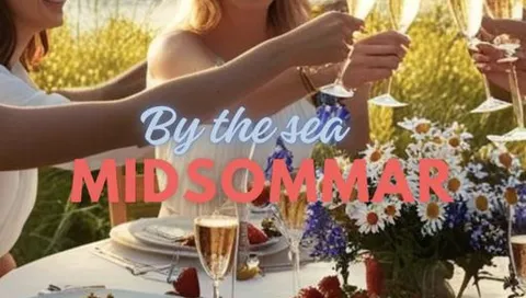 Personer skålar med champagneglas vid dukat bord utomhus, med sommarblommor och texten “By the sea MIDSOMMAR”.